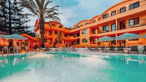 A hotel with a swimming pool, outdoor seating, and a palm tree. - Ünsal Hotel (Fethiye)