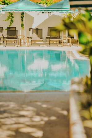 Una piscina al aire libre, sillones reclinables de piscina
