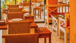 A restaurant with wicker chairs and tables, a glass wall, and a view of the outdoors. - Ünsal Hotel (Fethiye)
