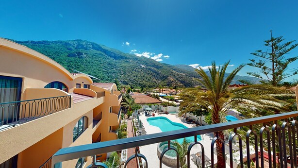 A hotel with a pool, balconies, and a view of mountains. - Ünsal Hotel (Fethiye)