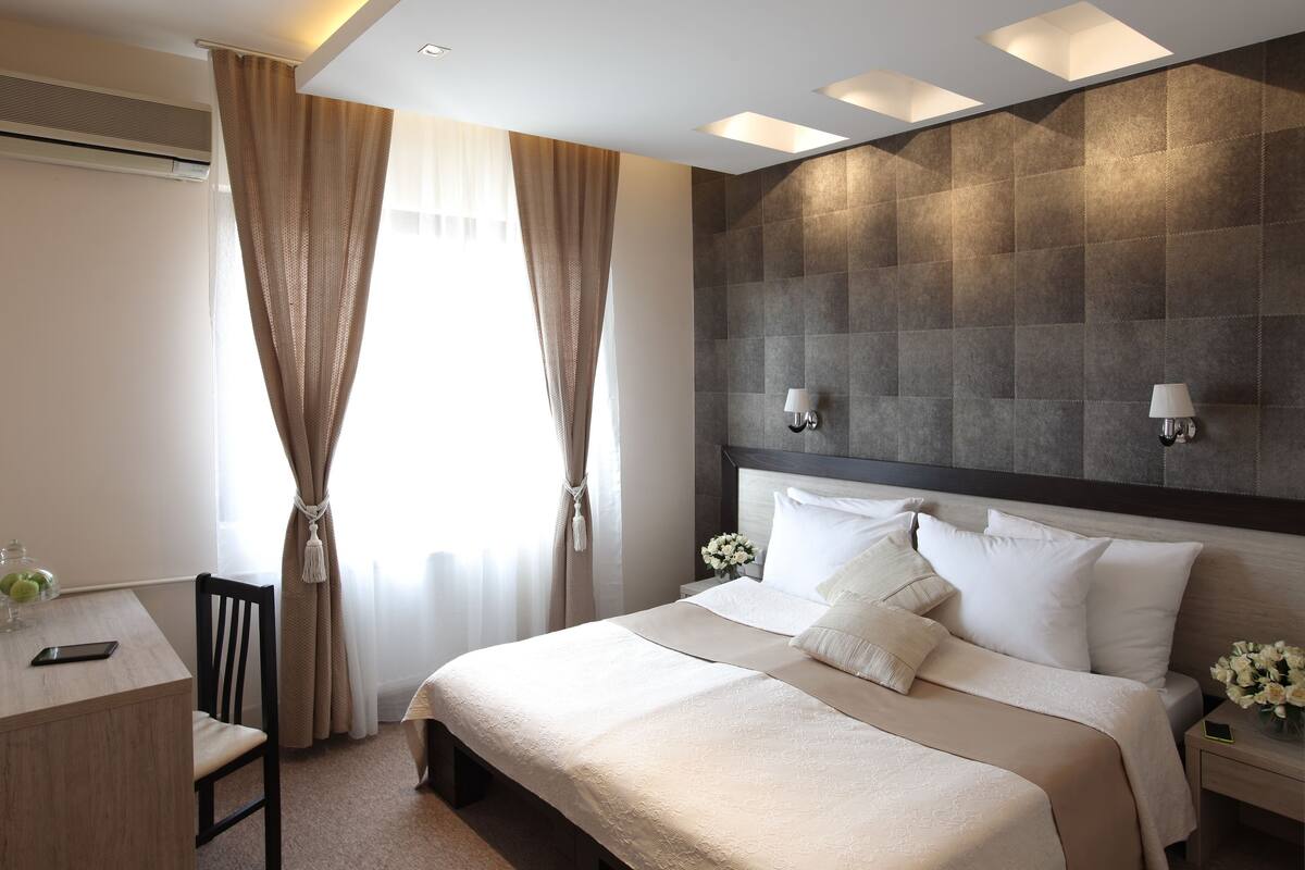 A hotel room with a bed, bedside tables, a desk, and a chair.
