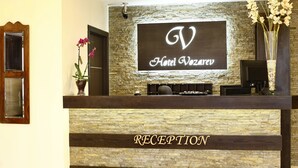 A reception desk with a stone facade and a sign that reads "Hotel Vozaruv." - Hotel Vozarev (Belgrade)