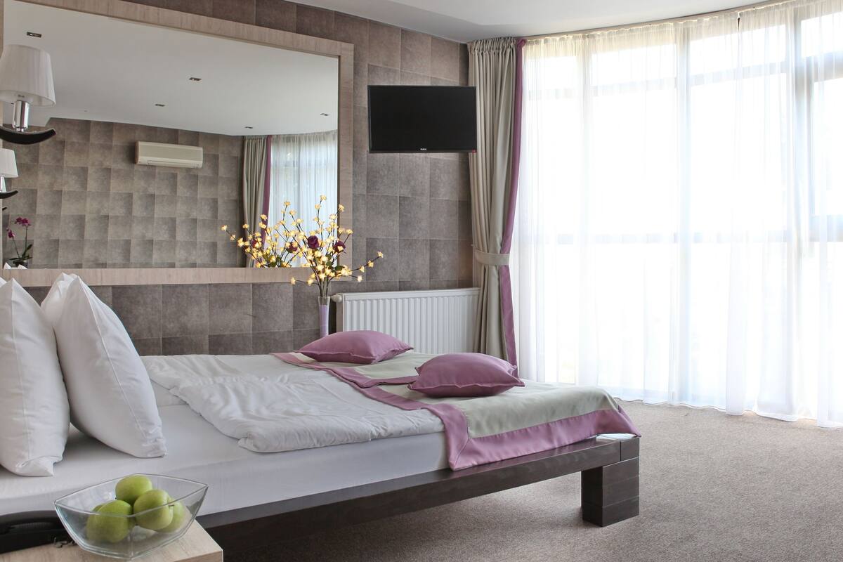 A modern bedroom with a bed, bedside table, lamp, and a TV mounted on the wall.