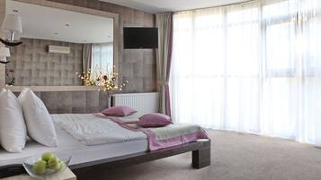 Un dormitorio moderno con cama, mesita de noche, lámpara y televisión montada en la pared.