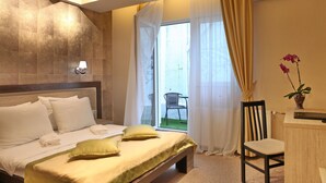 A modern hotel room with a large bed, a desk, and a view of the outside. - Hotel Vozarev (Belgrade)