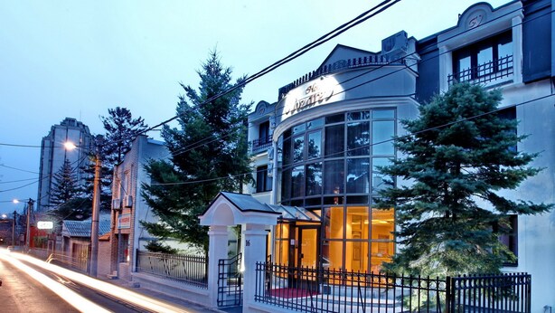 A hotel with a curved facade, large windows, and a red carpet entrance. - Hotel Vozarev (Belgrade)