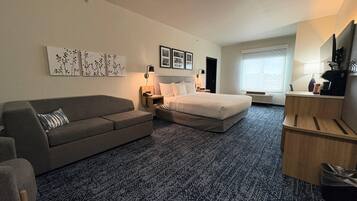 Ein Hotelzimmer mit Bett, Sofa, Schreibtisch und Fenster.