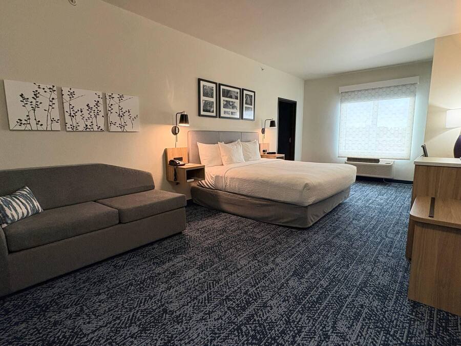 Ein Hotelzimmer mit Bett, Sofa, Schreibtisch und Fenster.