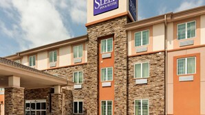 A Sleep Inn & Suites building with a stone facade, multiple windows, and a clear sky. - Sleep Inn & Suites Fort Scott (Fort Scott)