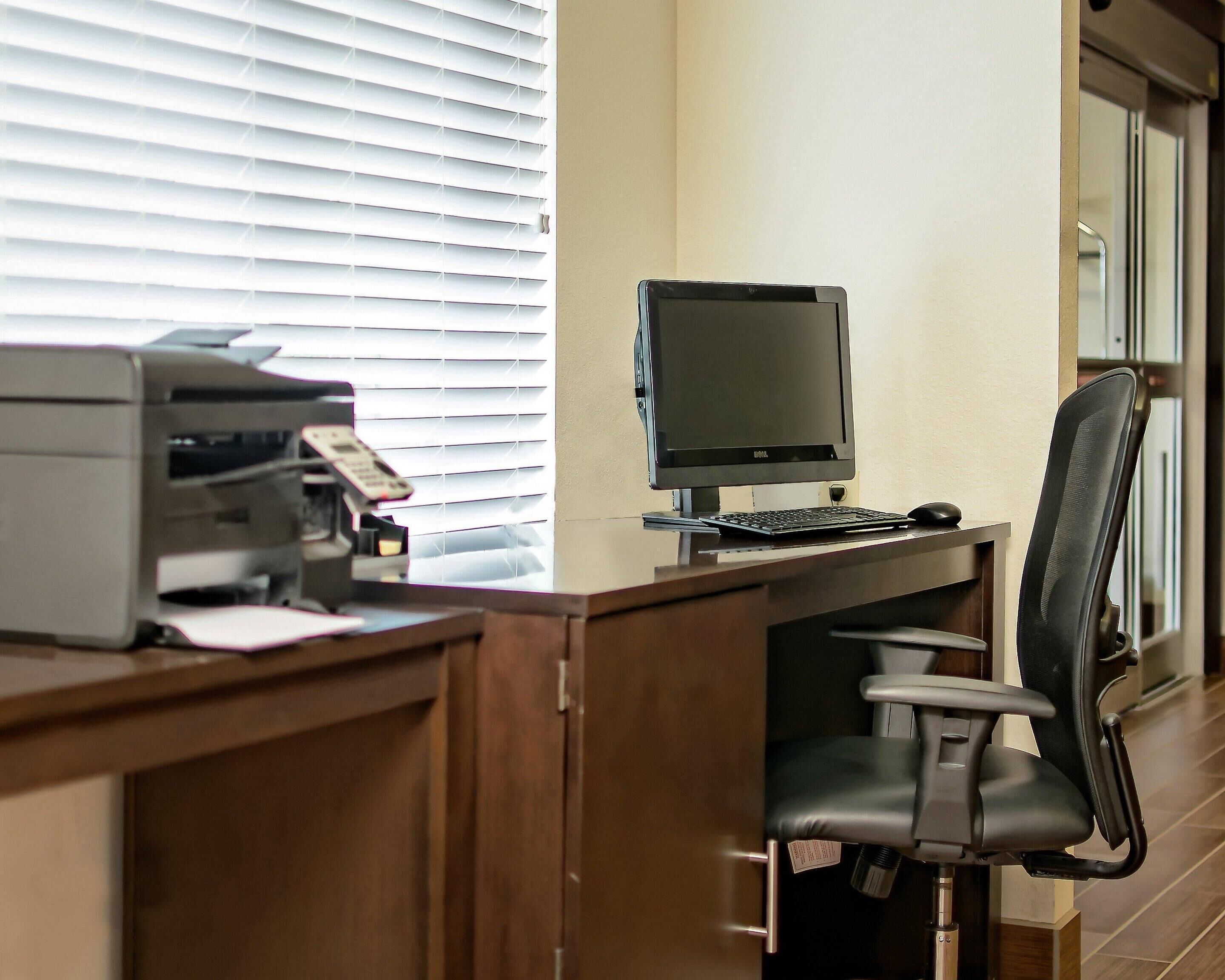 Un bureau d’ordinateur équipé d’un écran, d’un clavier et d’une souris, ainsi que d’une imprimante et d’une chaise.