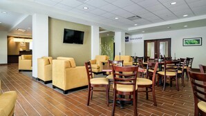 A hotel lobby with sofas, a TV, a 'Team Lounge' sign, and a reception desk. - Sleep Inn & Suites Fort Scott (Fort Scott)