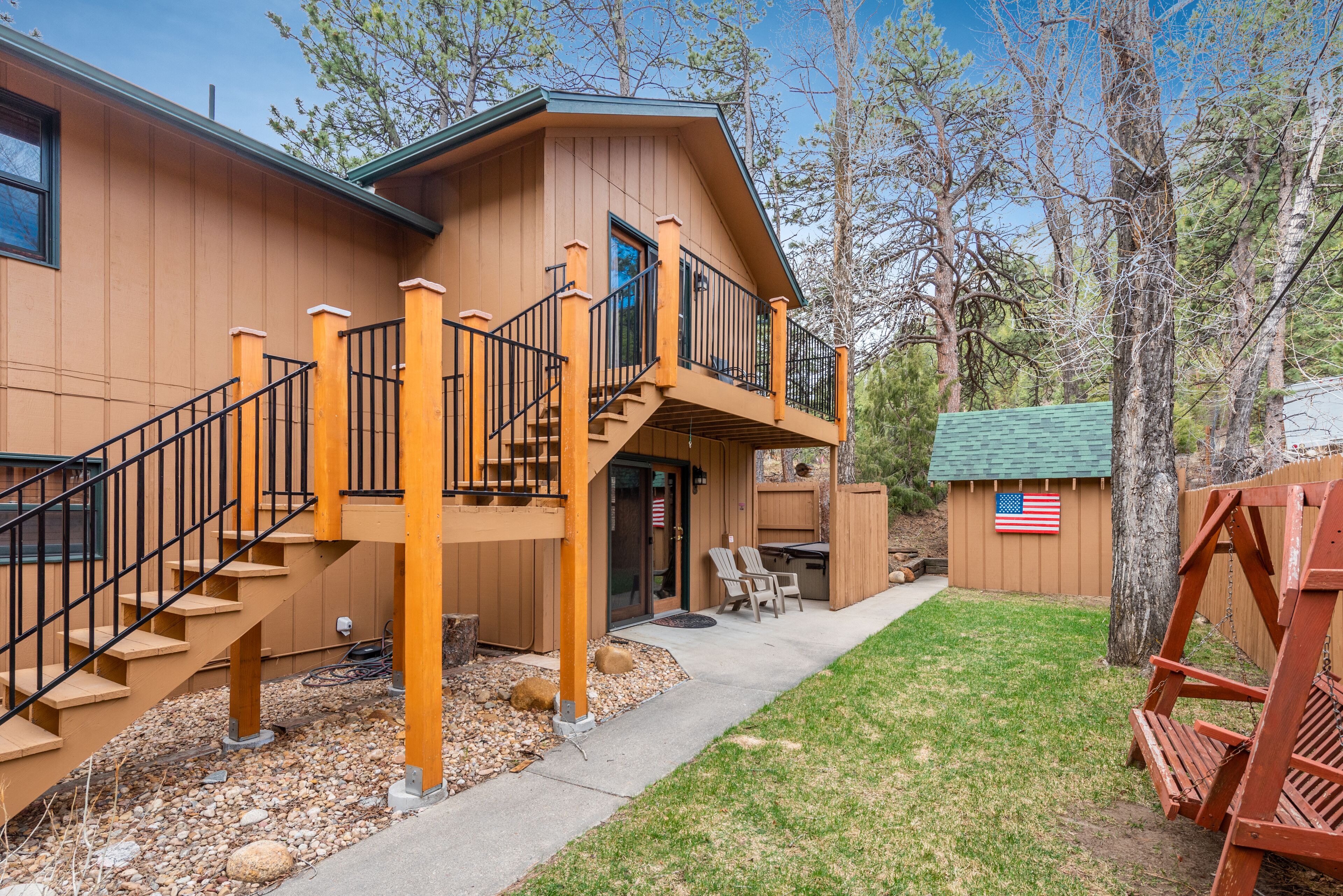 A two-story house with a balcony, a deck, and a small outdoor seating area.