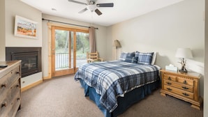 A bedroom with a bed, dresser, and a fireplace. - 4 Seasons Inn on Fall River (Estes Park)