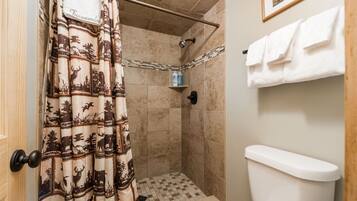 A bathroom with a shower area, a toilet, and a towel rack.