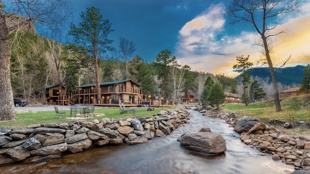 A lodge with a stone wall and a stream. - 4 Seasons Inn on Fall River (Estes Park)
