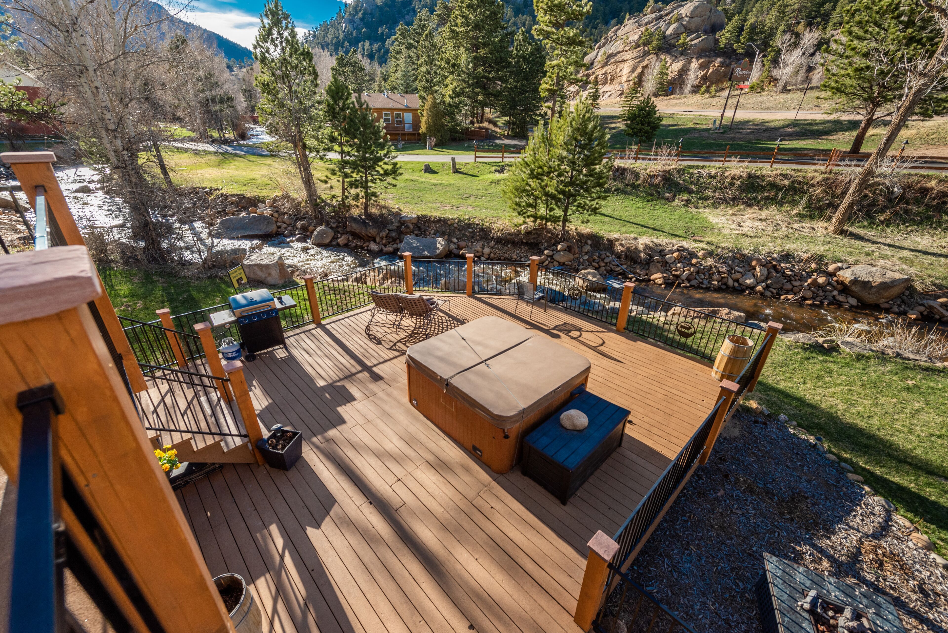 Eine Holzterrasse mit Sitzgelegenheit im Freien, einem Whirlpool und Blick auf eine Berglandschaft.
