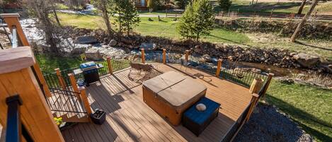 Eine Holzterrasse mit Sitzgelegenheit im Freien, einem Whirlpool und Blick auf eine Berglandschaft.