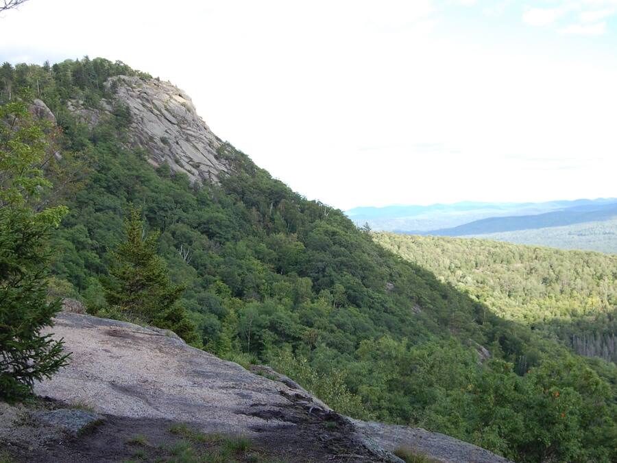 A mountainous landscape with dense forest and rocky terrain.
