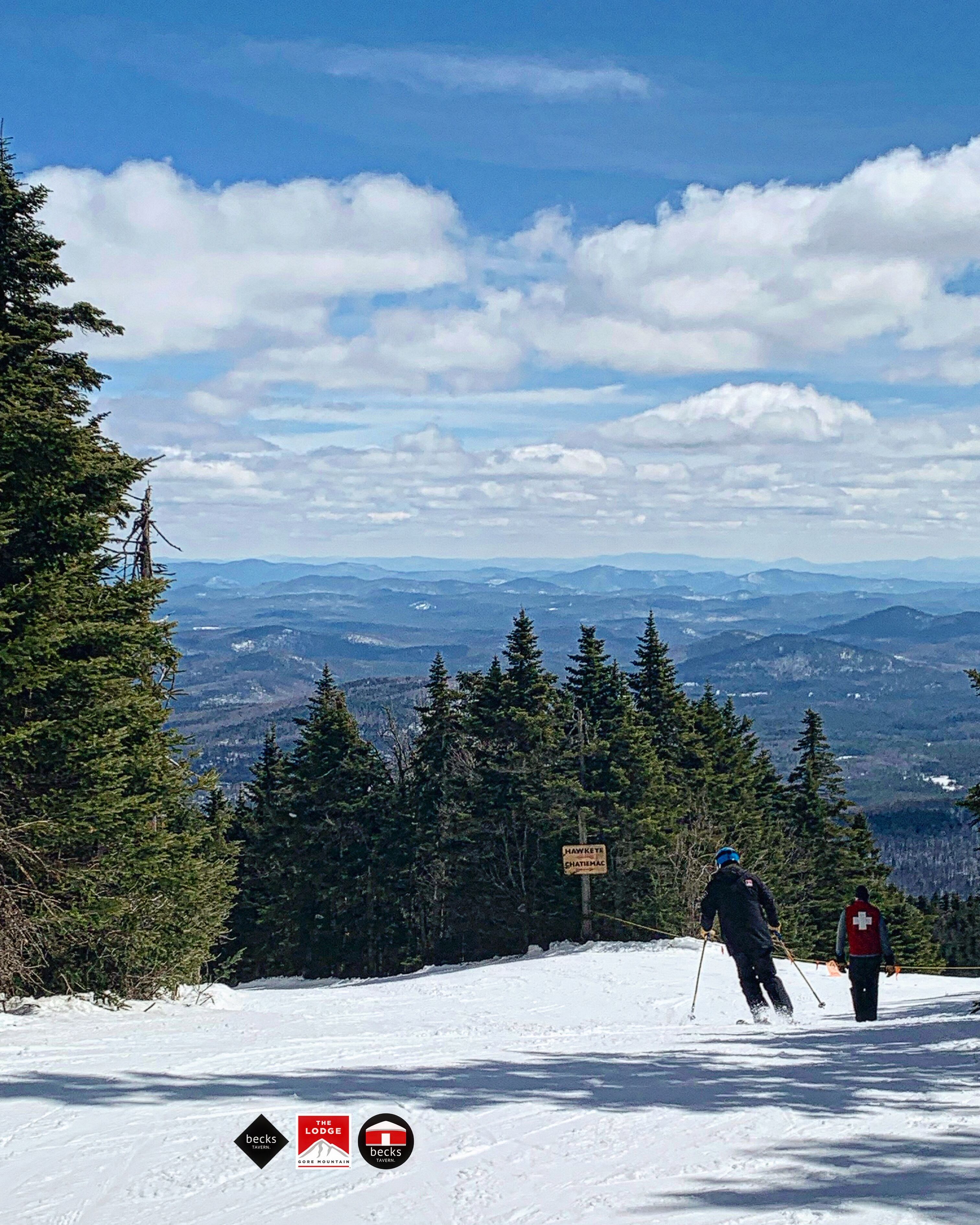 A snowy mountain landscape with skiers, a sign indicating 'Hawk's Nest', and logos for 'Becks Tavern' and 'The Lodge'.