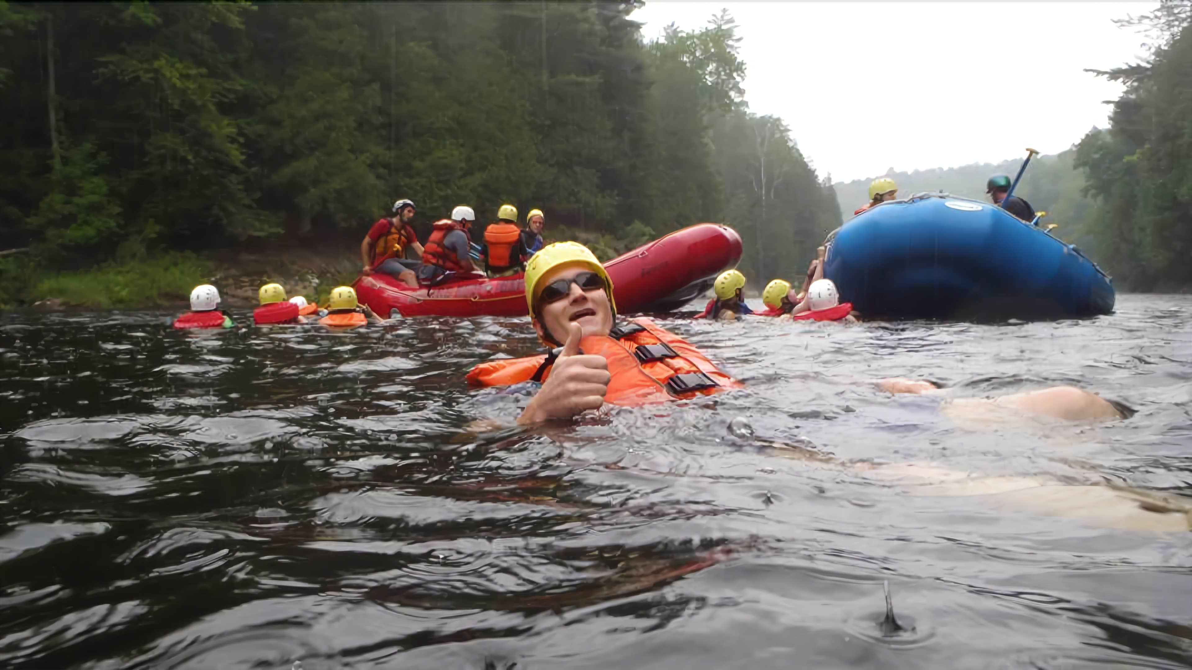 A group of people on inflatable rafts in a river surrounded by trees.