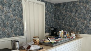 Una cocina con salpicadero de azulejos blancos, encimera de madera y diseño de papel tapiz floral.