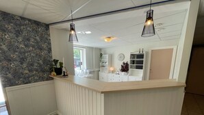 Un área de recepción con un mostrador de madera, estanterías blancas y una pared con estampado floral.
