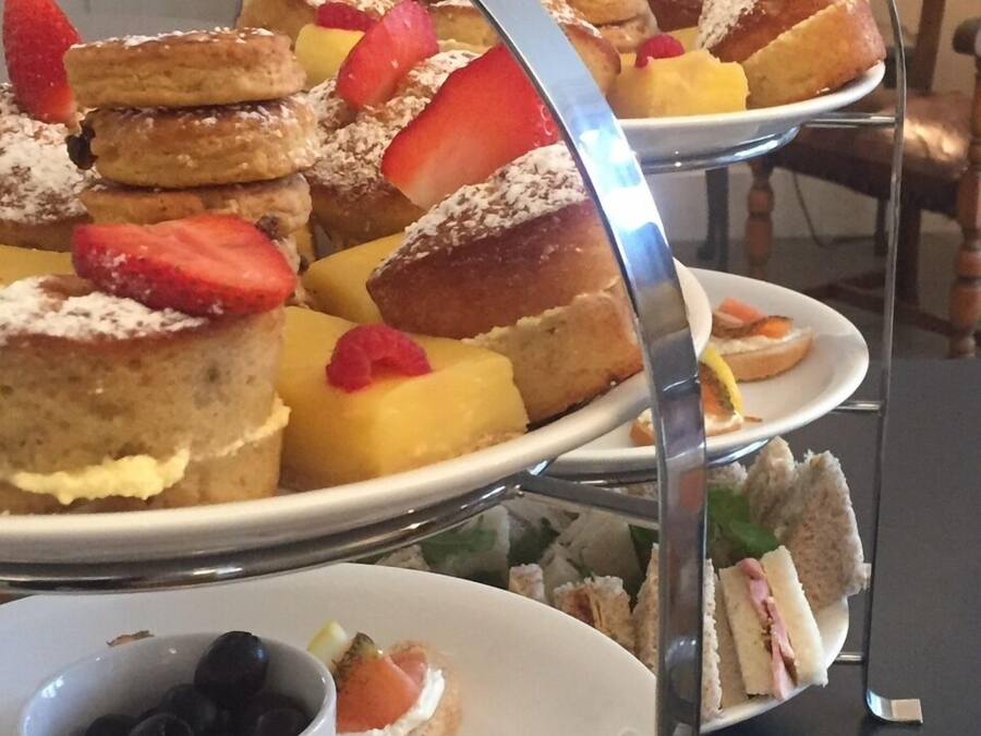 Un présentoir à trois niveaux, garni de diverses pâtisseries et de sandwichs.