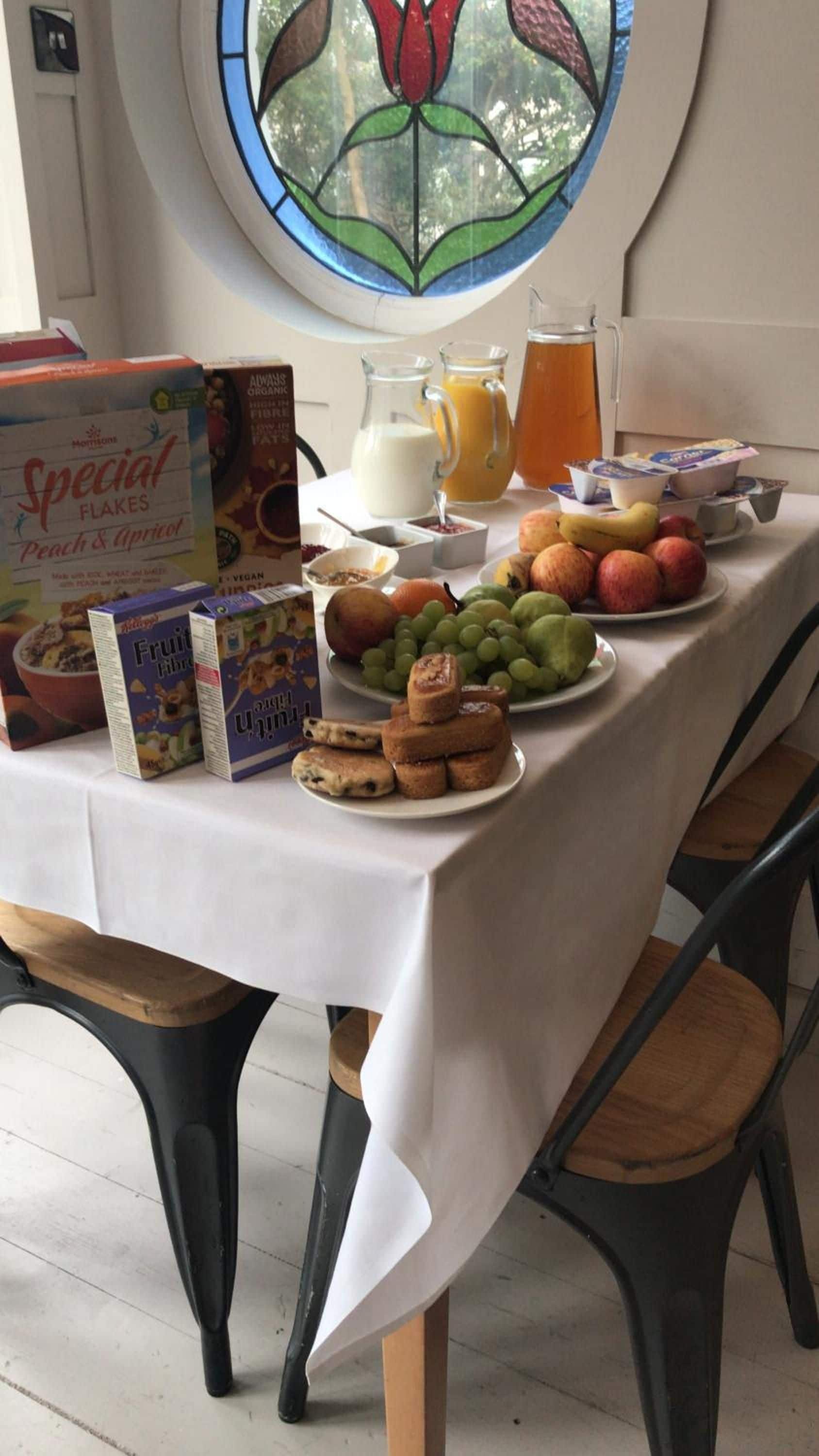 A breakfast table with food items, a fruit bowl, and a juice pitcher.