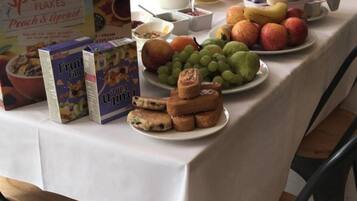 A breakfast table with food items, a fruit bowl, and a juice pitcher.