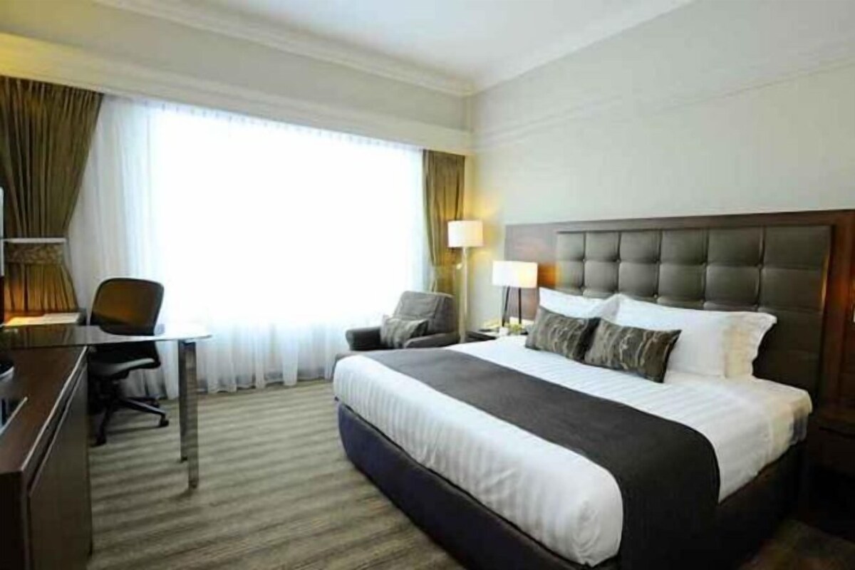 A hotel room with a large bed, a desk, and a chair.