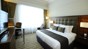 Una habitación de hotel con una cama grande, un escritorio con televisor y una silla.