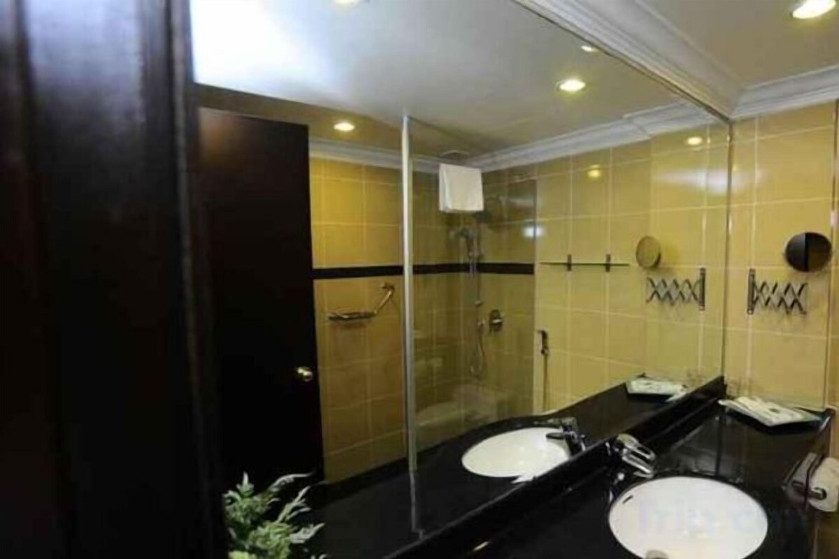 A bathroom with two sinks, a glass shower enclosure, and a mirror.