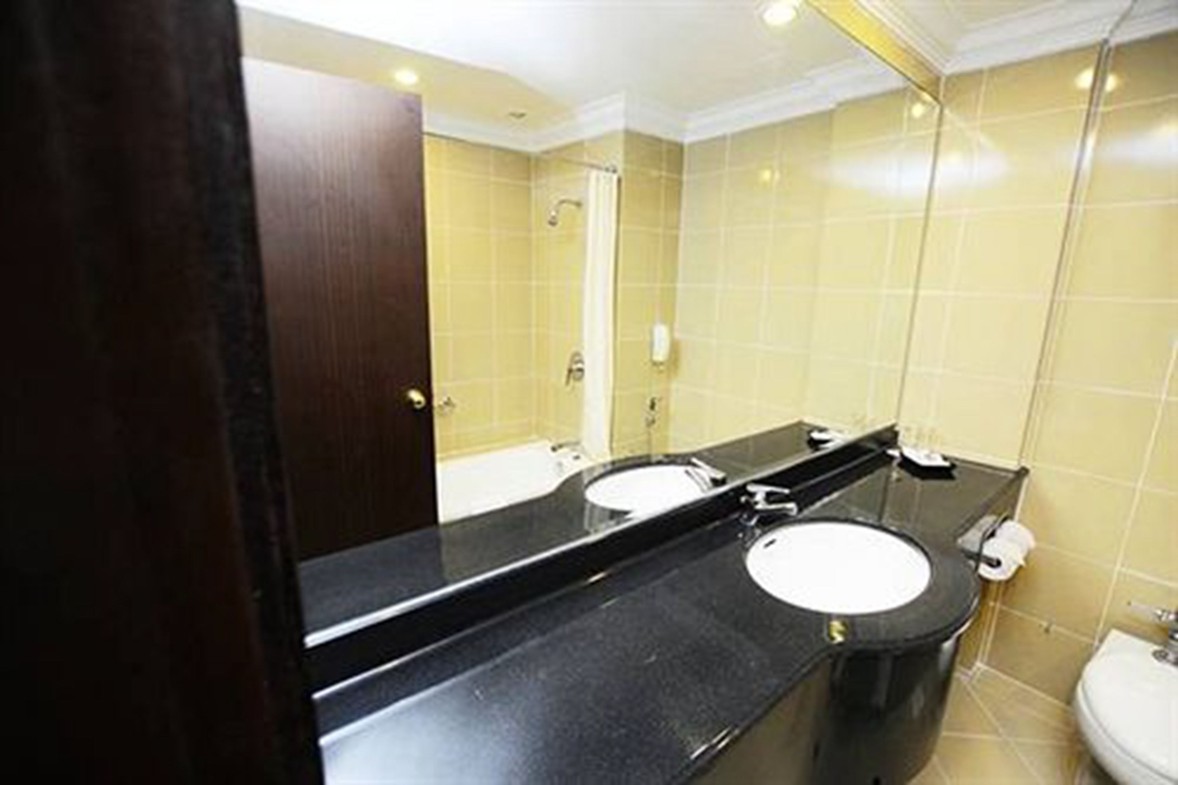 Un baño con dos lavamanos, un espejo y un inodoro.