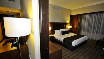 A hotel room with a bed, bedside lamps, a desk, and a chair.