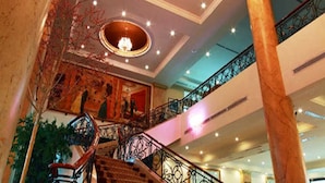 Un vestíbulo espacioso con una escalera, un techo ornamentado y un candelabro.