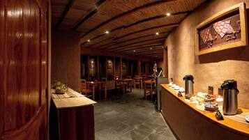Un restaurante con vigas de madera en el techo, suelo de piedra y una barra con opciones de café y té.