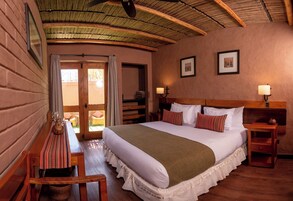 Un dormitorio acogedor con una cama grande, cabecera de madera y techo de paja.