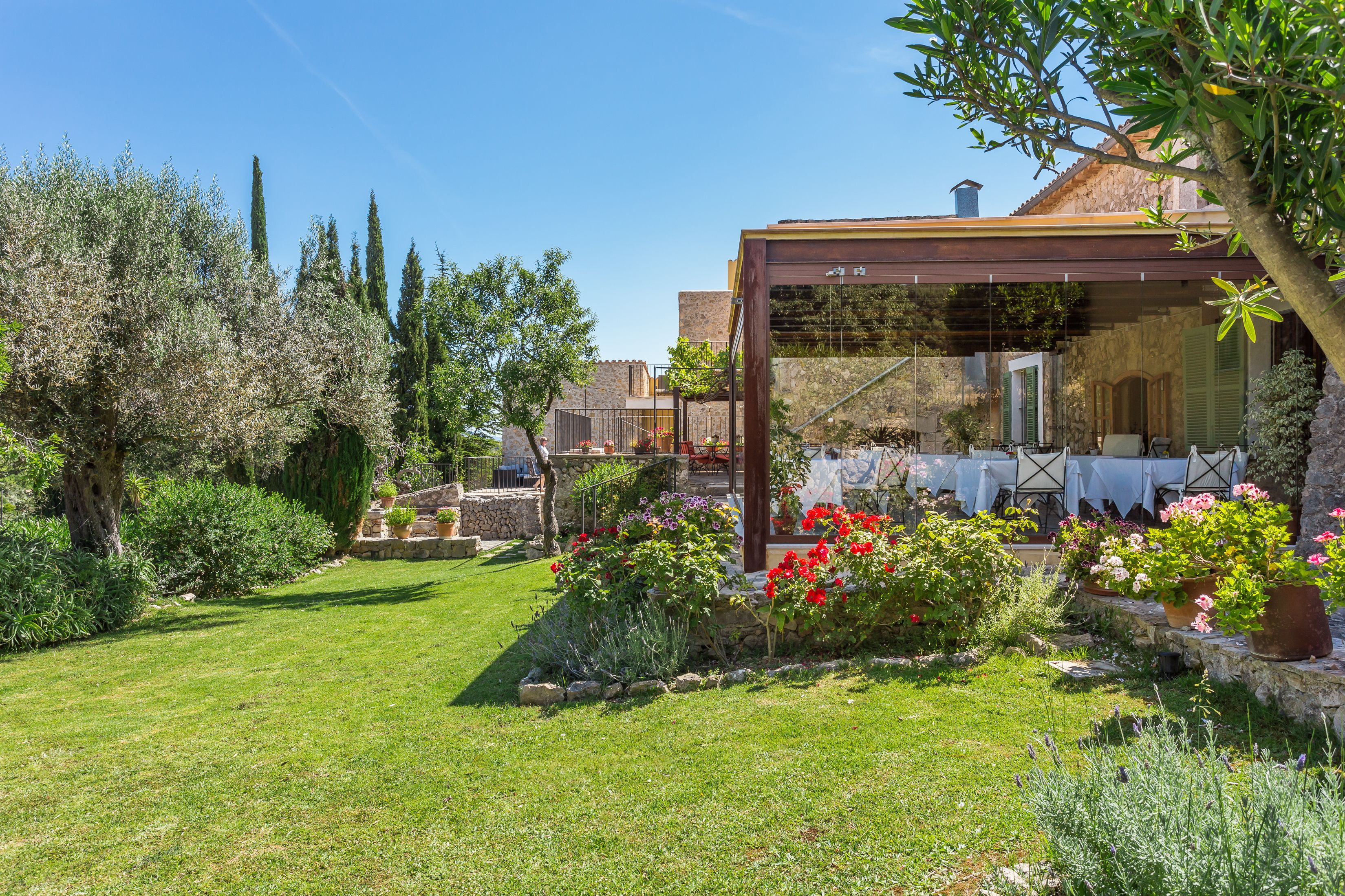 A garden with a pergola, stone walls, and potted plants.