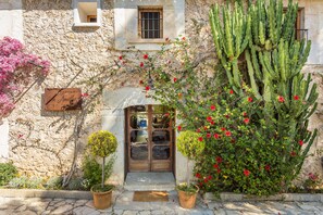 A stone building with a wooden door, potted plants, and a cactus. - Finca Son Ametler (Selva)