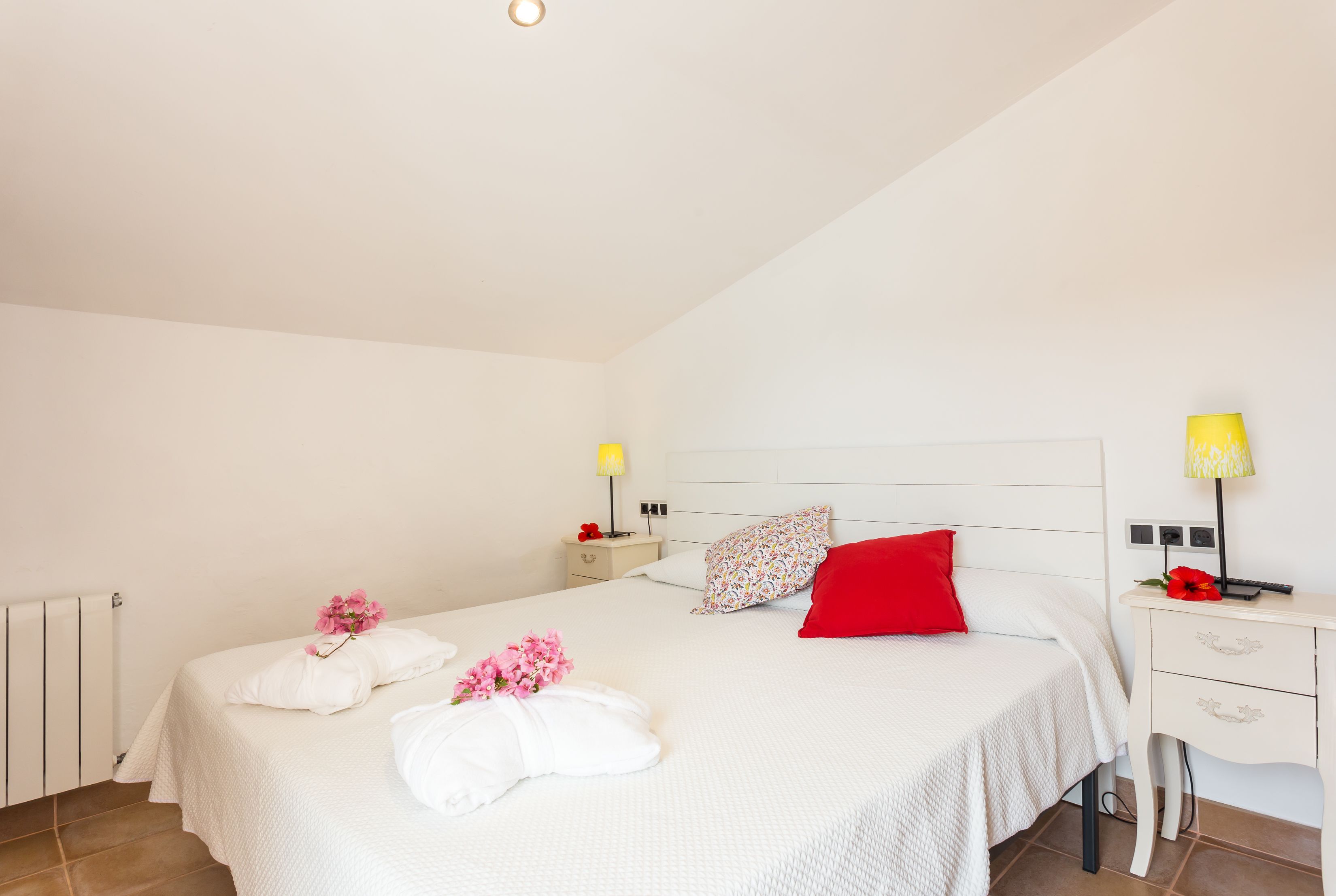 Un dormitorio ordenado con dos camas, mesitas de noche, lámparas y un radiador.