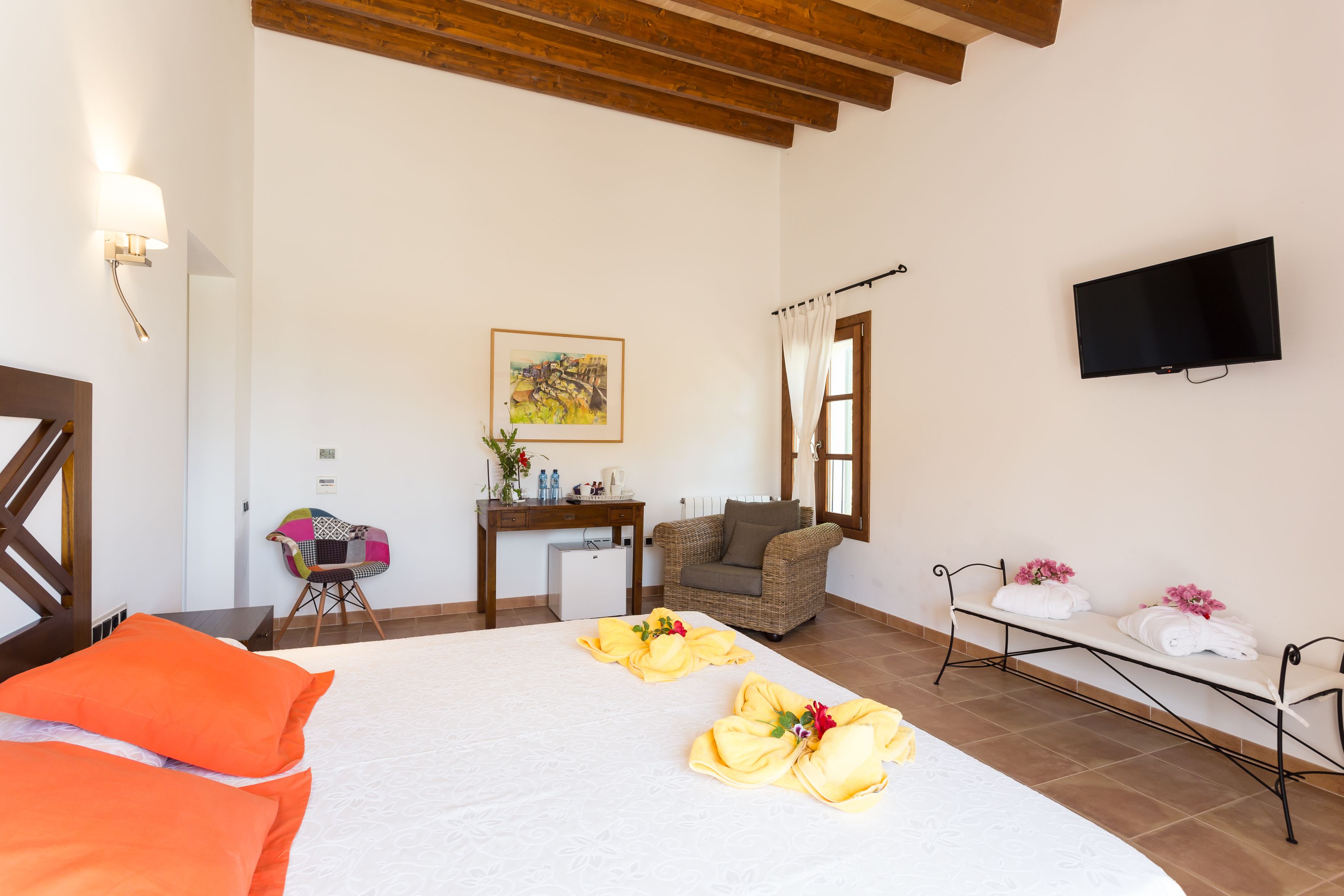 Habitación de hotel con cama, escritorio, silla, televisión y ventana con cortinas.