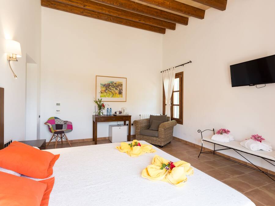Habitación de hotel con cama, escritorio, silla, televisión y ventana con cortinas.