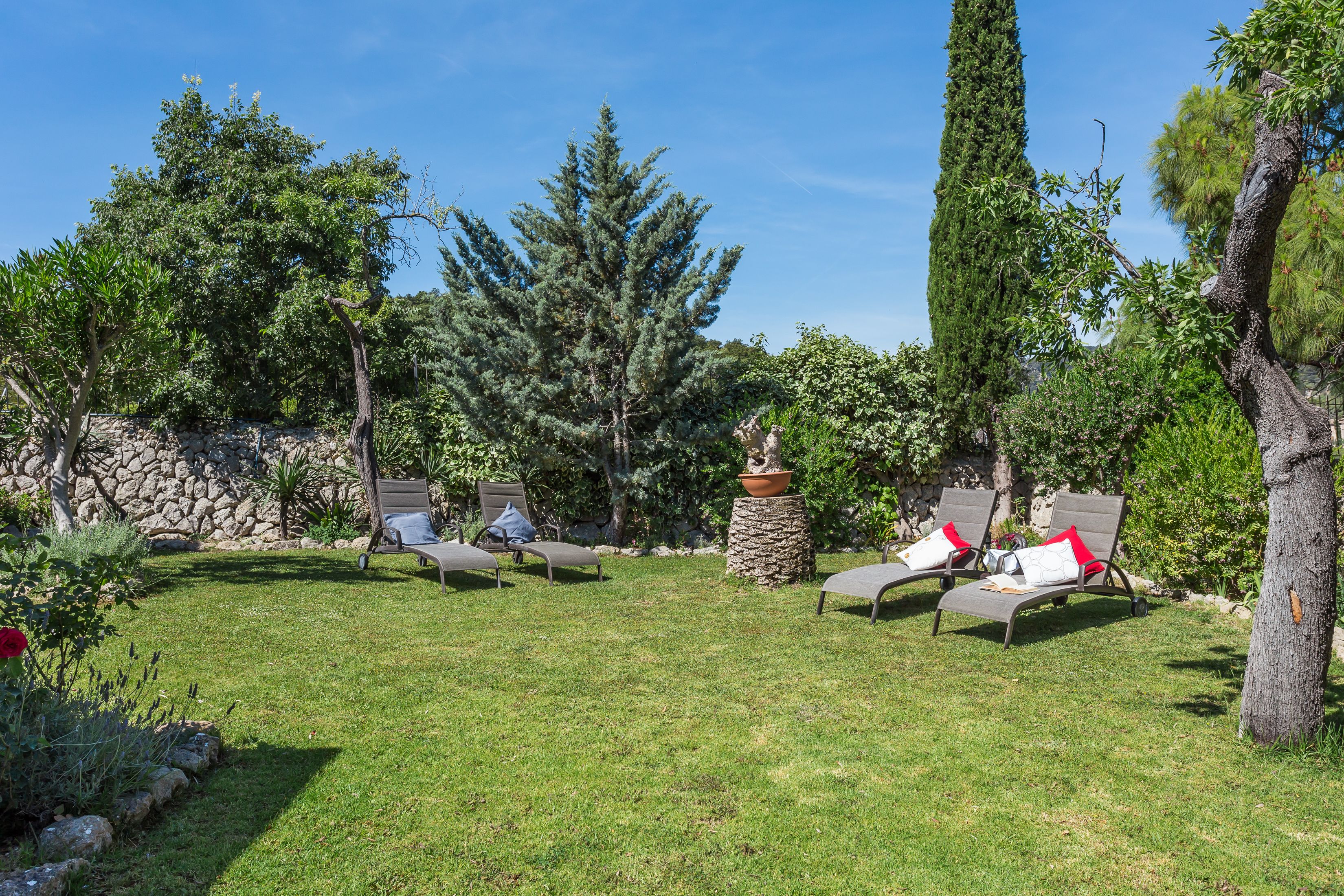 A garden with lounge chairs and a stone wall.