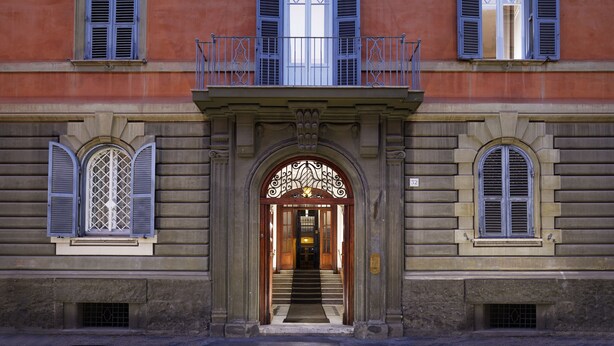 A building with a central entrance, multiple windows with shutters, and a balcony with ornate railings. - San Pietro Boutique Rooms (Rome)
