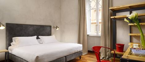 A neatly arranged hotel room with a bed, a desk, a chair, and a window with curtains.