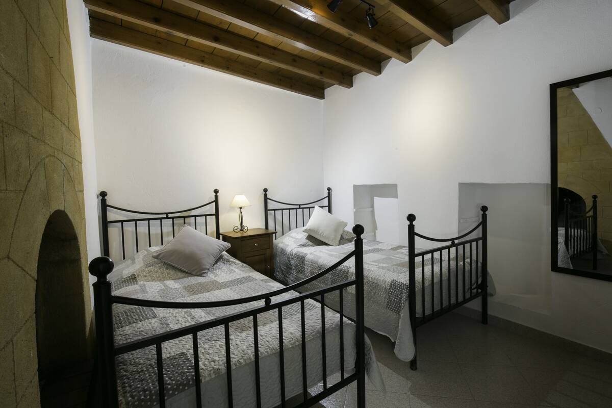 Un dormitorio con dos camas, vigas de madera en el techo y un espejo grande en la pared.