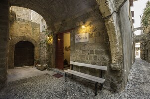 A stone building with a bench, a door, and a sign reading "Cydokia".