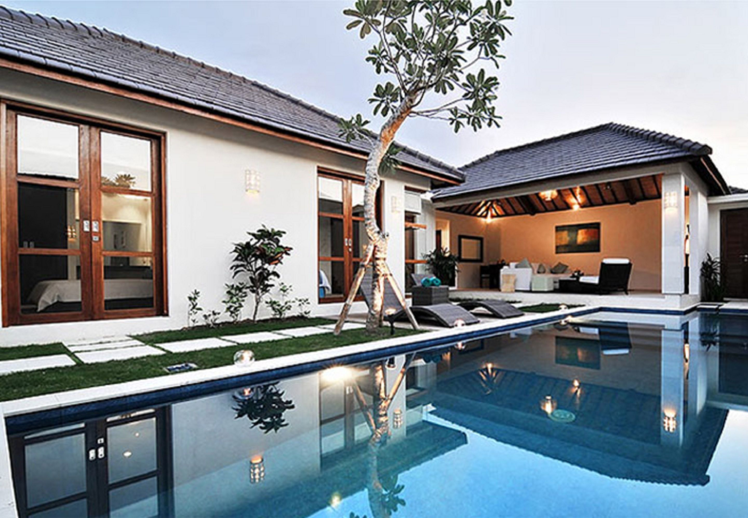 Une maison moderne dotée d’une piscine, de grandes fenêtres et d’un espace patio.