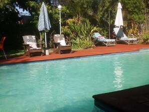 A swimming pool with lounge chairs and umbrellas. - Gloria's Bed and Breakfast (Livingstone)