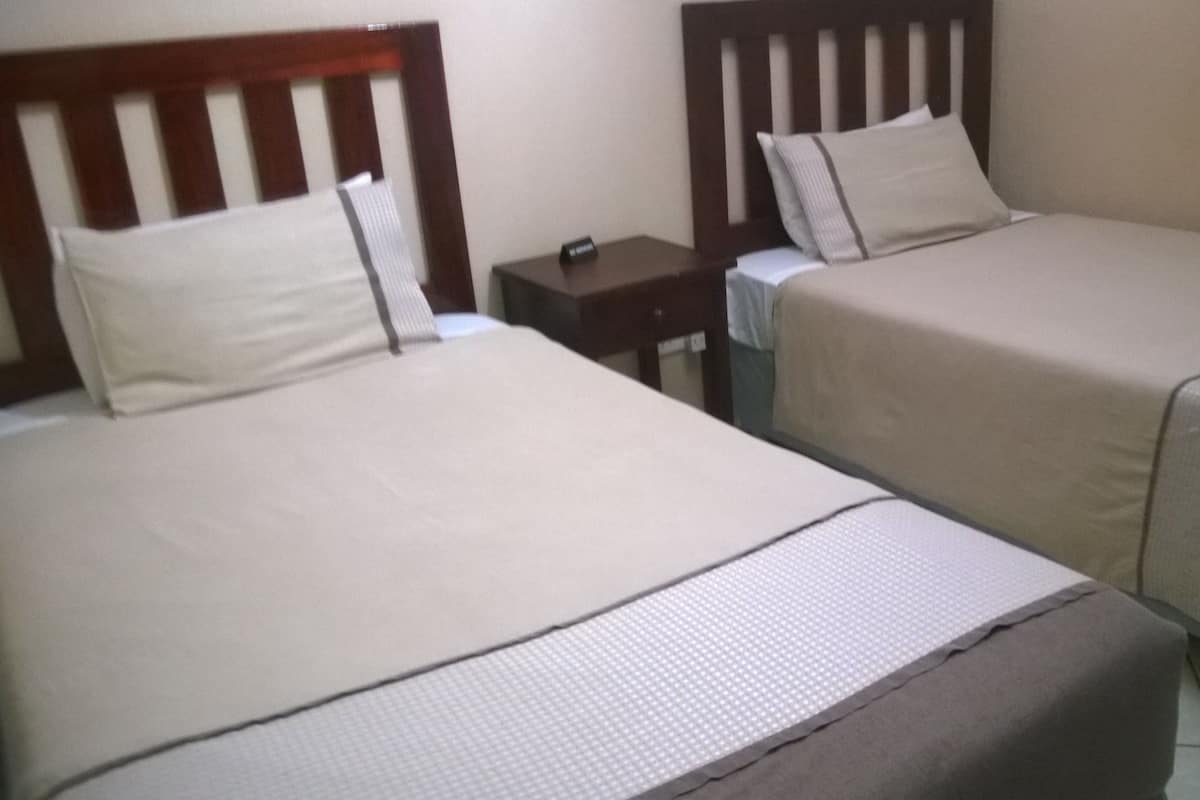 Two single beds with wooden headboards, a small bedside table, and a nightstand.